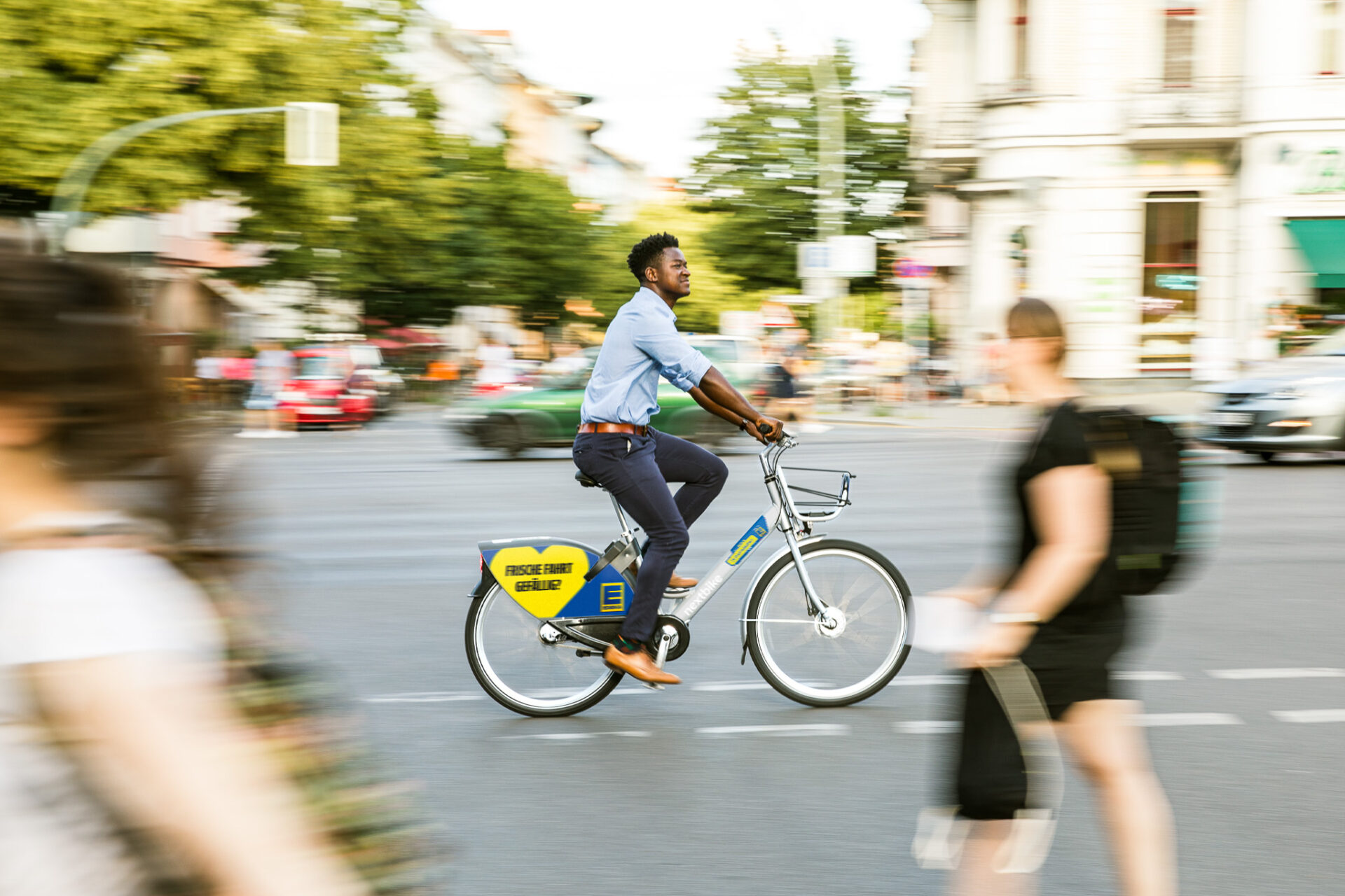 Ein Mann auf einem nextbike Berlin Leihfahrrad fahrend auf einer Straße. Seine Umgebung leicht verschwommen.