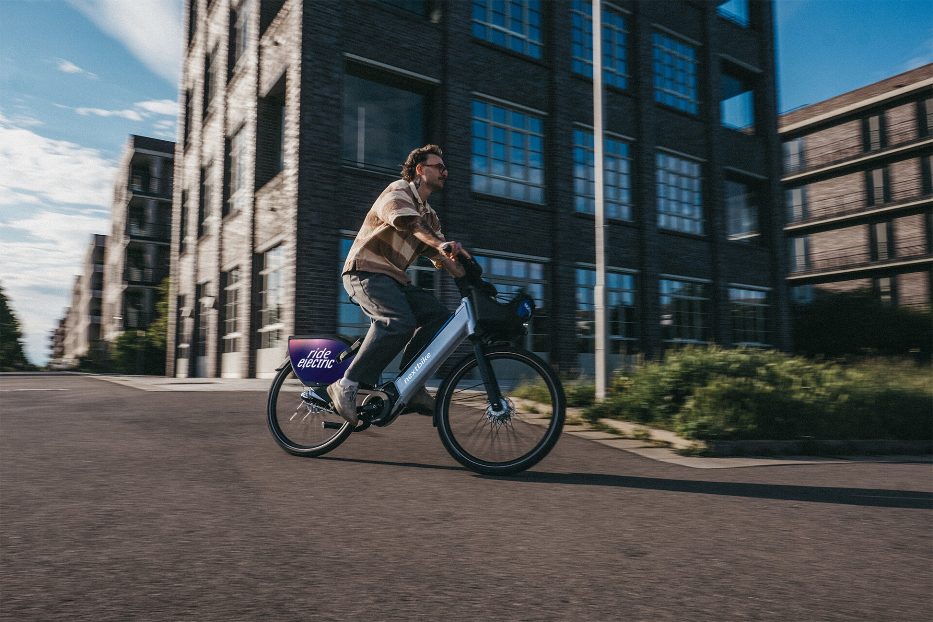 Junger Mann fährt mit einem nextbike E-Bike um eine Kurve.